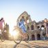 Personas dando un paseo en bicicleta frente al Coliseo romano