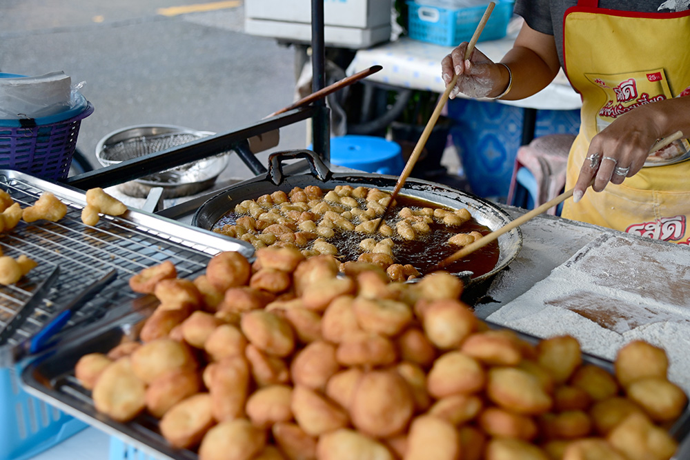 Mujer cocinando comida callejera tailandesa