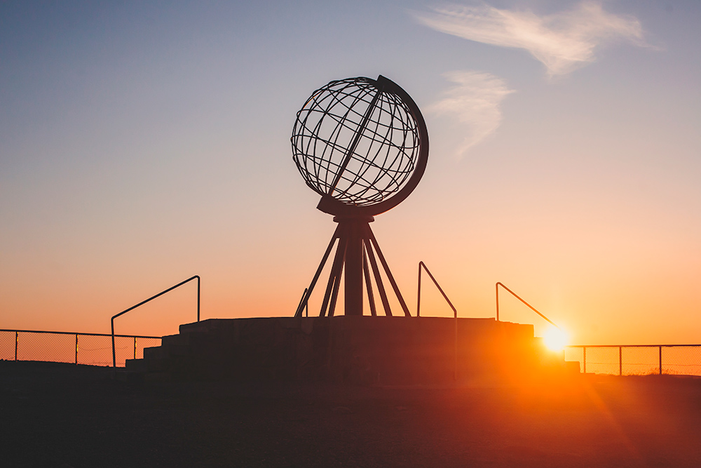 Una bola del mundo echa de hilos de metal bajo un atardecer.