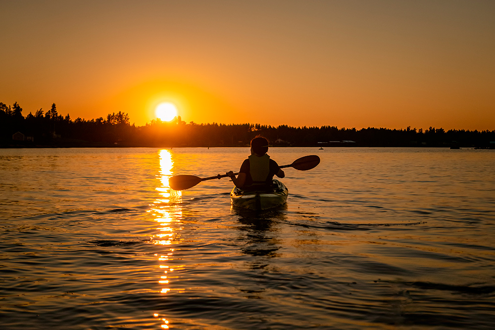 Un lago bajo el atardecer con una persona en kayak