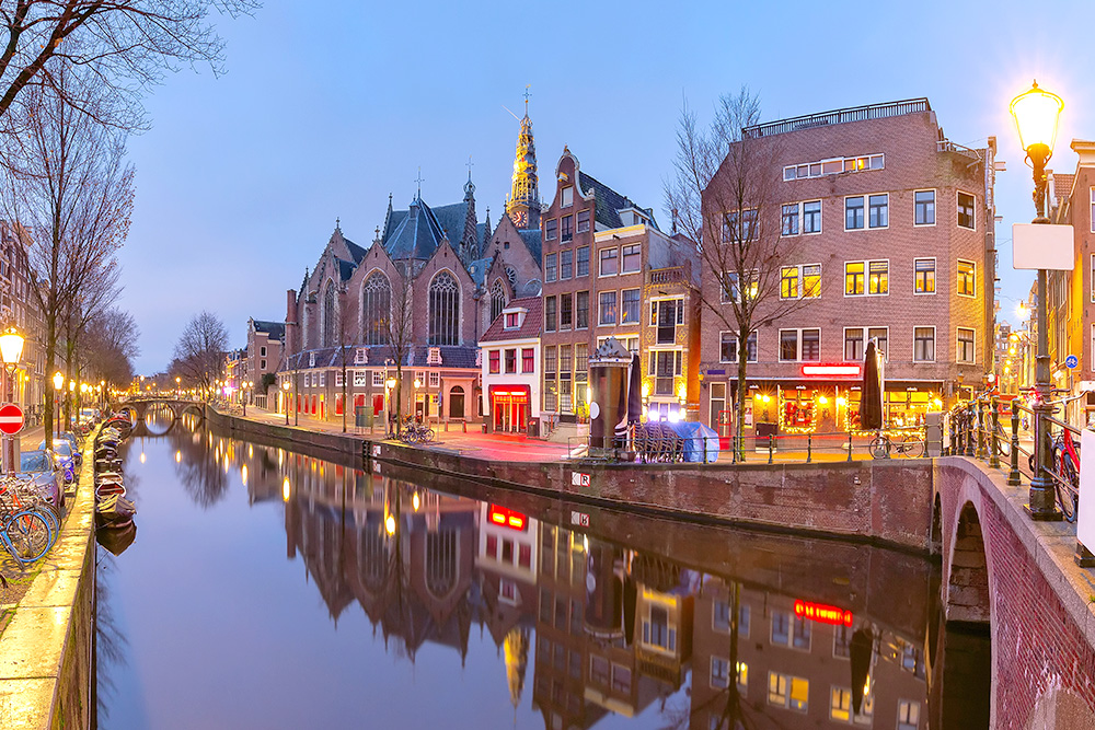 Un canal de Ámsterdam. En una de sus orillas edificios clásicos todos con iluminación roja.