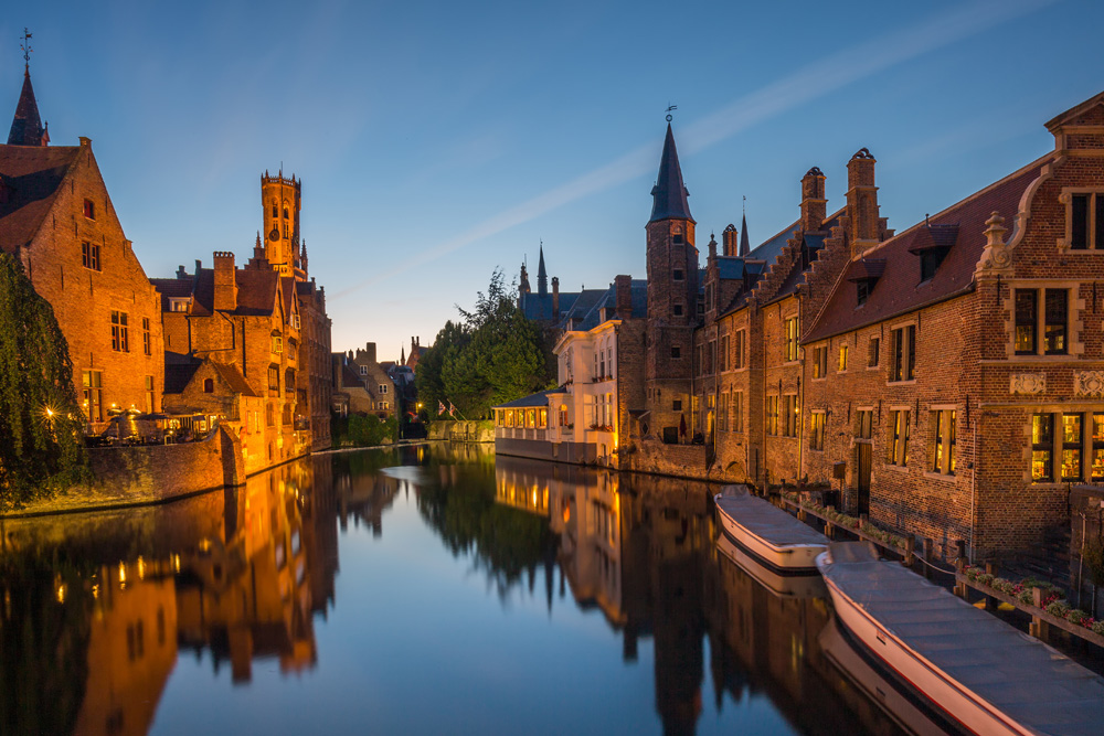 Un canal con casas a ambos lados y barcas. En un atardecer
