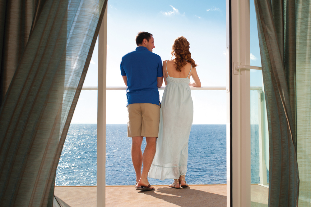 Hombre y mujer mirando el mar desde un balcón de espaldas.