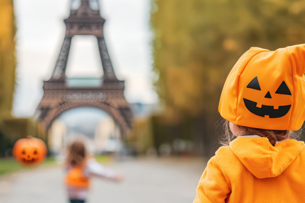 Primer plano de un niño de espaldas con un disfraz de calabaza. Al fondo difuminada la Torre Eiffel