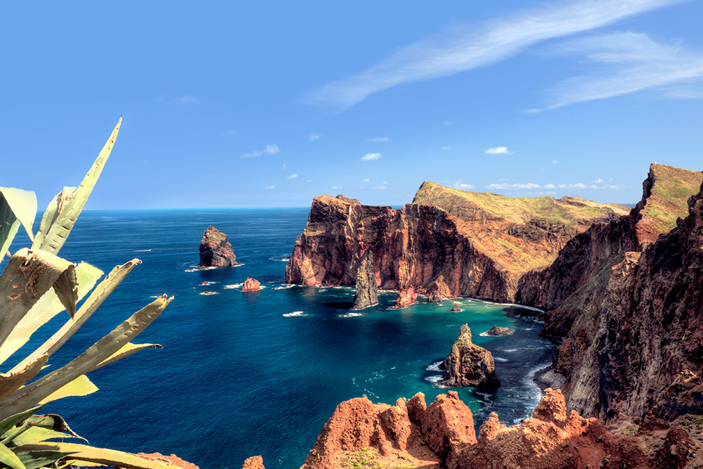 Imagen de una bahía rodeada piedra marron y un mar azul marino