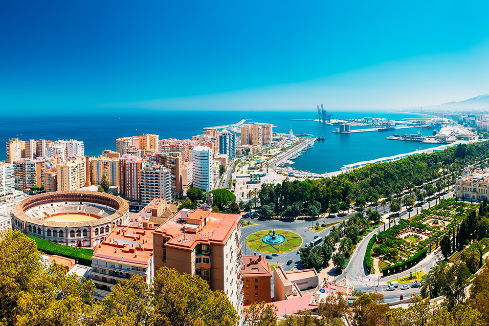 Vista aérea del puerto, plaza de toros y edificios rodeados de arboles verdes