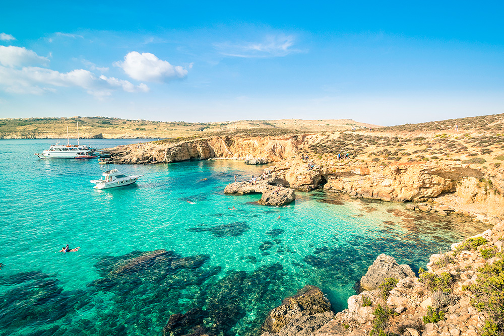 Pequña bahía de mar azul turquesa con dos pequeñas embarcaciones blancas