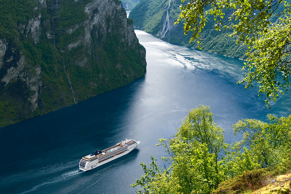 un curcero surcando en un mar azul marino entre dos montañas 