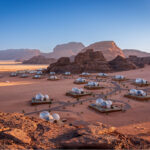 Desierto bajo el cielo azul. Tierra en tonos marron y tiendas blancas 